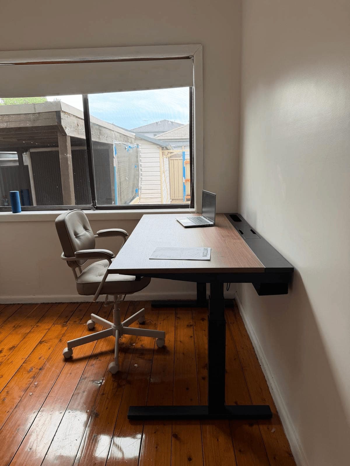 IKEA electric sit-stand desk with a timber top and black frame, assembled beside a window in a home study