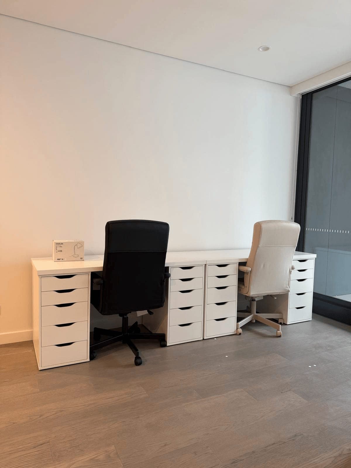 Two-person workstation with white desk tops on four IKEA ALEX drawer units and two office chairs