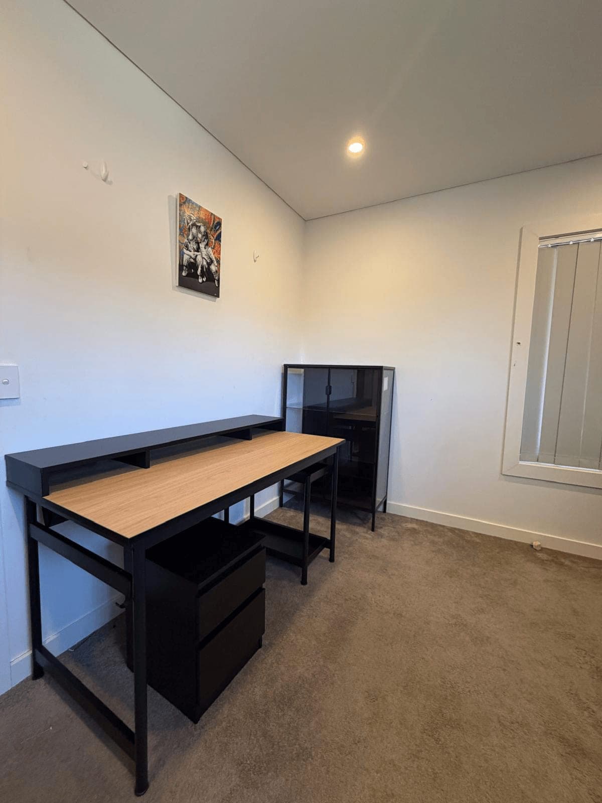 Black metal frame desk with a timber top, monitor shelf and pedestal drawer unit, assembled in a carpeted study