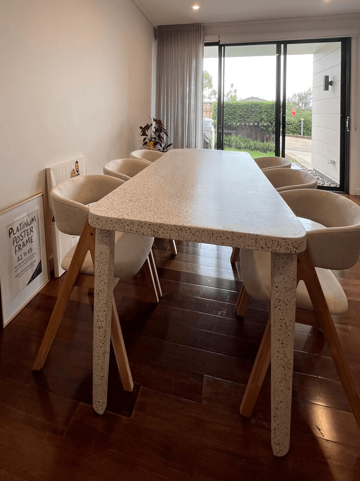 Speckled stone-top dining table on timber legs with six upholstered chairs, assembled in a dining room beside sliding doors