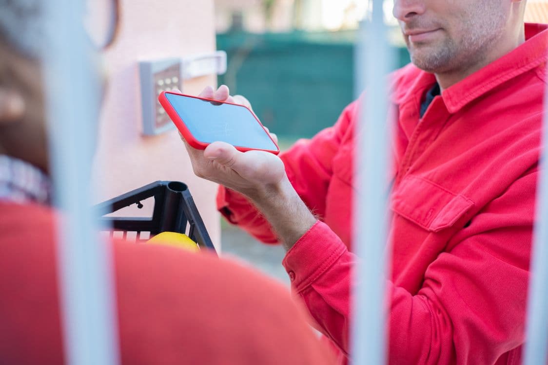 Handyman in uniform showing a fixed-price quote on his phone