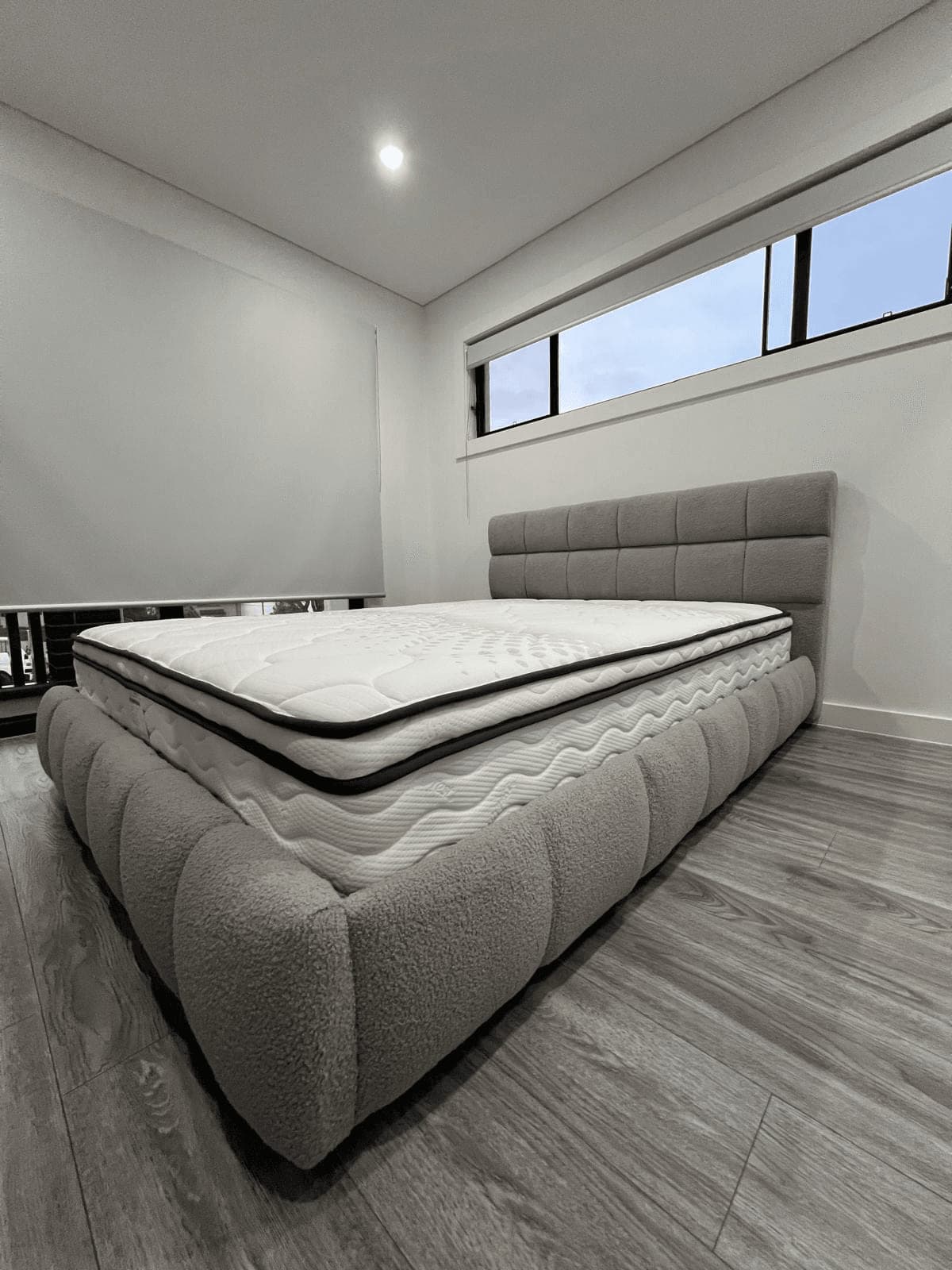 Grey fabric upholstered bed with a panelled headboard, assembled by Liztty with the mattress placed ready for use