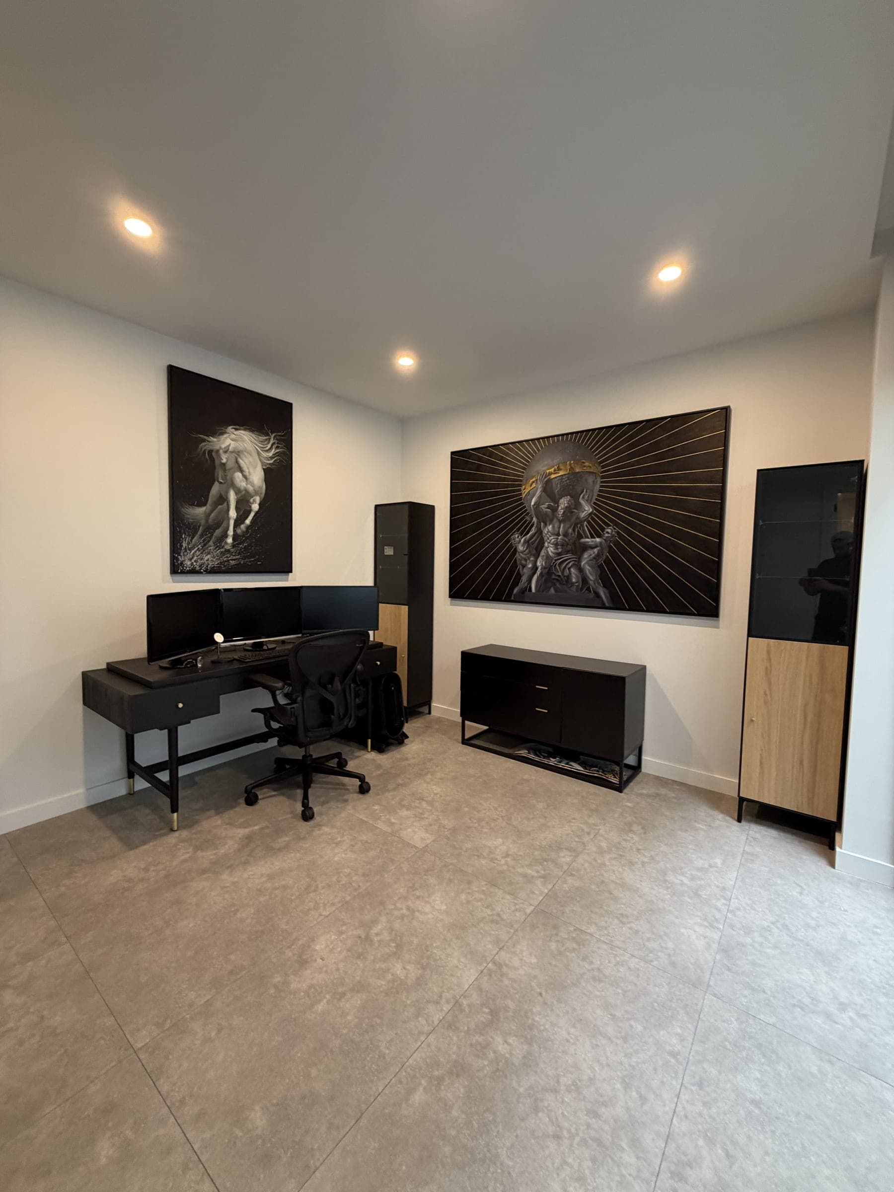 Dark timber executive desk with a triple-monitor setup and ergonomic chair, assembled by Liztty in a home office